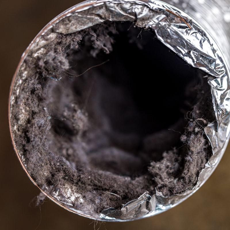 an open dryer vent with lint lining the insides